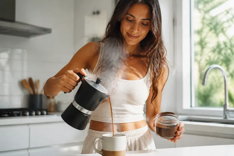 Femme préparant une tasse de café aux champignons dans sa cuisine ensoleillée, illustrant la tendance des boissons bien-être.