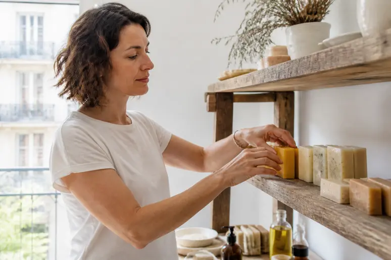 Une femme arrange des savons artisanaux dans un atelier parisien, soulignant la fabrication française et la composition naturelle du produit.