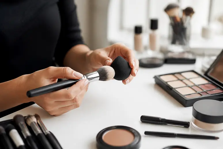 Pinceau de maquillage professionnel et éponge blender posés sur une coiffeuse lumineuse