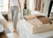 Plusieurs culottes invisibles confortables pliées dans un panier en lin sur une commode lumineuse.