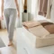 Plusieurs culottes invisibles confortables pliées dans un panier en lin sur une commode lumineuse.