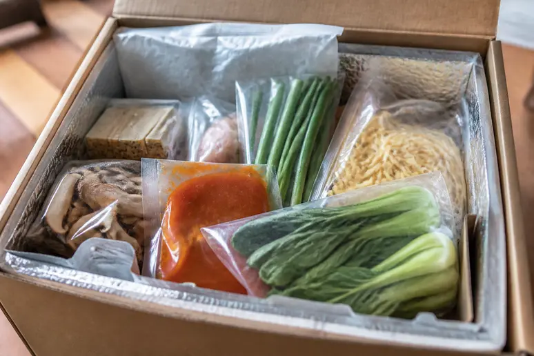 Colis de box repas ouvert contenant des ingrédients frais et des éléments réfrigérants pour l'avis hello fresh