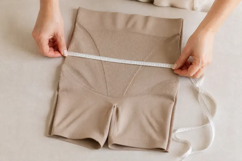 Mesure avec un mètre ruban souple sur un sous-vêtement sculptant plié