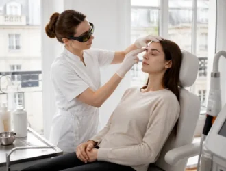 Une dermatologue examine attentivement les sourcils d'une cliente avant une séance de détatouage sourcils en cabinet.