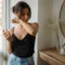 Une femme élégante teste comment choisir parfum longue tenue abordable près d'une fenêtre lumineuse chez elle.