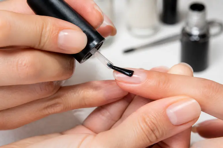 Application minutieuse d'une couche fine de vernis semi-permanent sur l'ongle