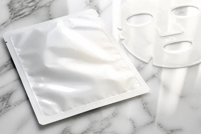Packaging d'un masque de soin en hydrogel posé sur une surface claire
