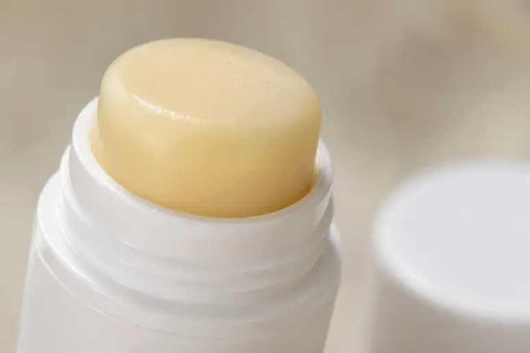Stick cosmétique repulpant ouvert posé sur un plan de travail neutre