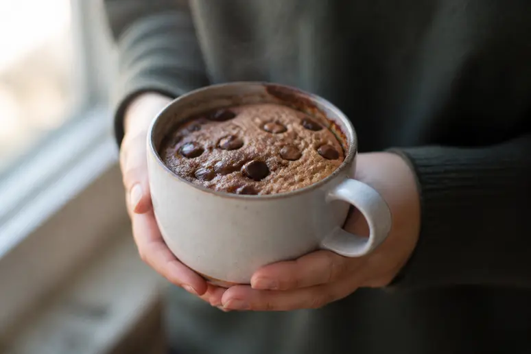 Un mug cake cookie tout juste cuit dans sa tasse avec des pépites de chocolat fondant