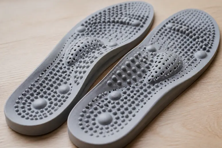 Paire de semelles Akusoli souples avec picots d'acupression posées sur une surface en bois.