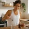 Une femme préparant sa boisson bien-être dans sa cuisine montre comment utiliser Simply Aloe au quotidien.