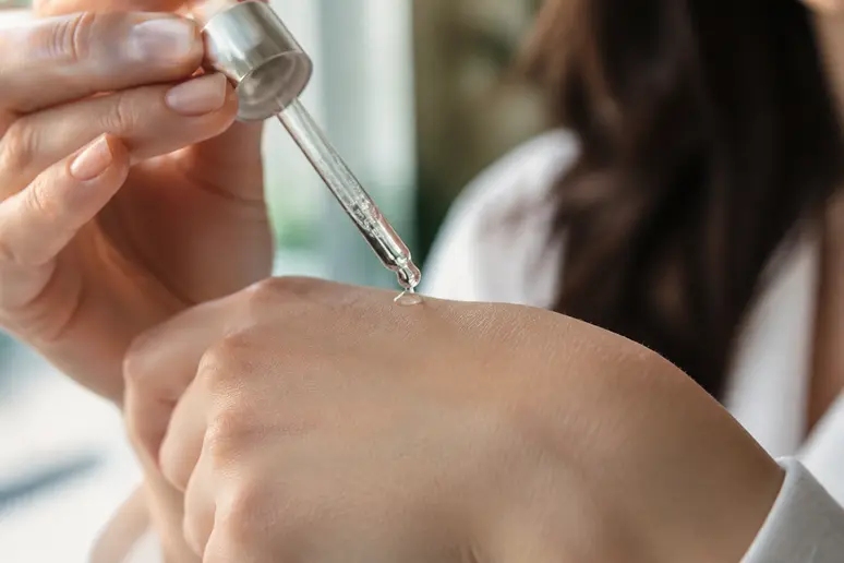 Gouttes de sérum antioxydant prélevées avec une pipette en verre avant l'application sur le visage