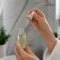 Flacon de sérum tenu en main pour illustrer une vitamine C routine visage adaptée.