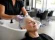 Femme aux cheveux blancs au bac d'un salon pour contrer l'effet bétadine cheveux blancs.