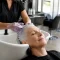 Femme aux cheveux blancs au bac d'un salon pour contrer l'effet bétadine cheveux blancs.