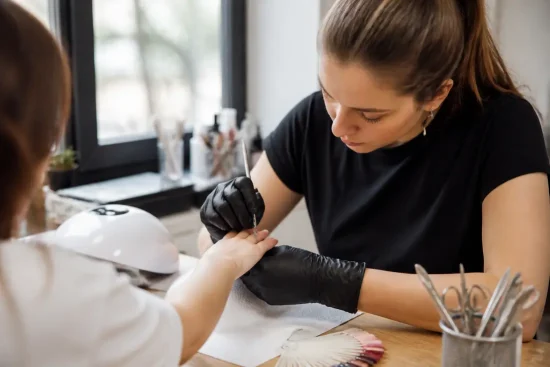 Gros plan sur les mains lors d'une manucure russe en salon de beauté avec des instruments professionnels.