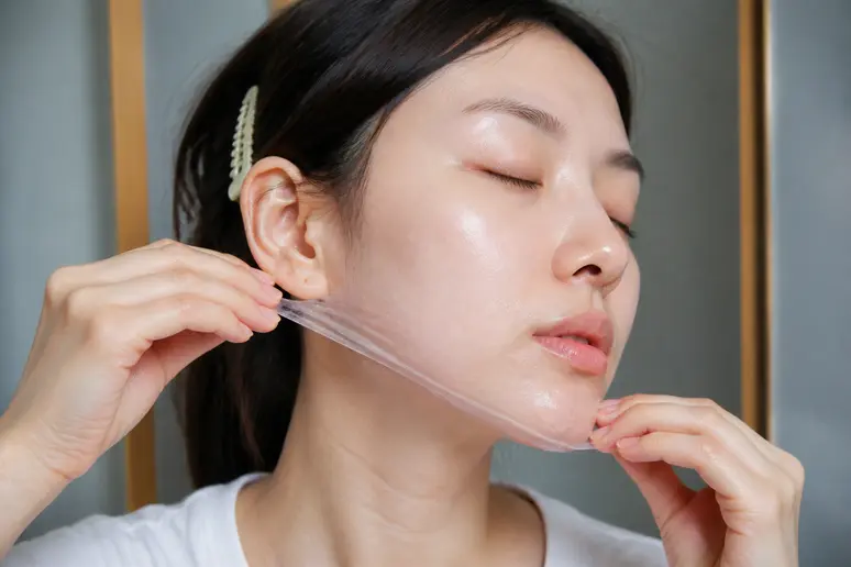 Geste d'application d'un masque de nuit hydratant sur le bas du visage.