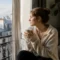 Jeune femme pensive près d'une fenêtre analysant la signification rêve mort personne vivante un matin d'automne